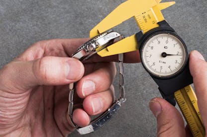 Using a caliper to measure the case thickness of a wristwatch from the side profile