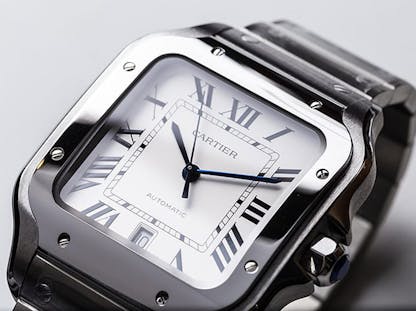Close-up of Cartier Santos wristwatch featuring Roman numerals and stainless steel case.