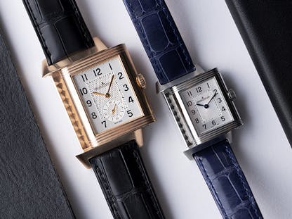 Pair of Jaeger-LeCoultre Reverso watches with rectangular cases and leather straps.