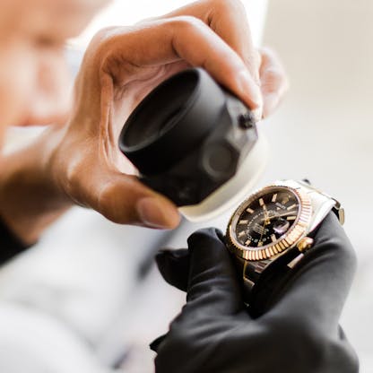 Watchmaker examining Rolex Sky-Dweller for authenticity using loupe
